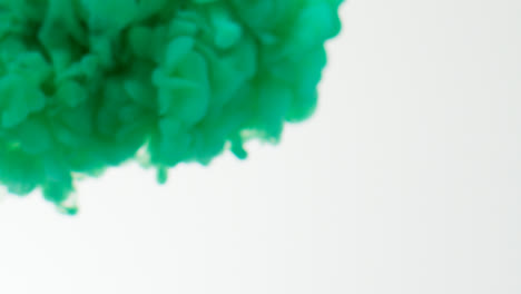 Green-Paint-Or-Dye-Dropped-Into-Water-Against-White-Background-To-Create-Swirling-Colourful-Smoke-Background